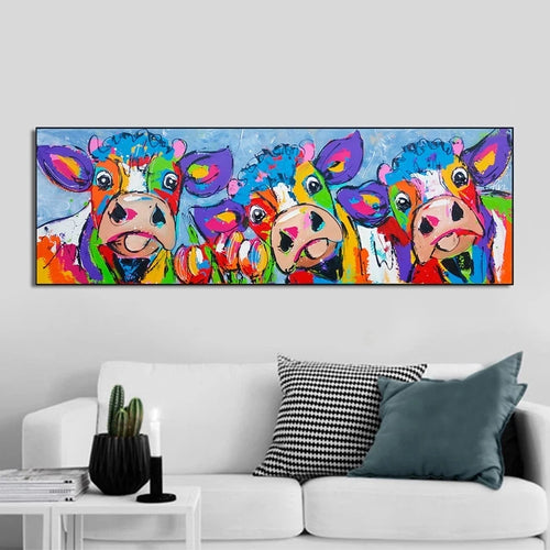 Colorful cow painting on a wall above a white sofa with decorative pillows.